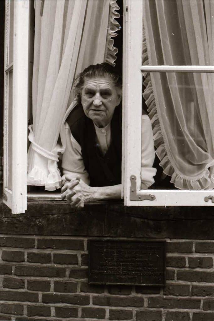 An 82 year-old leans out her window in a Hamburg street, 1984.
